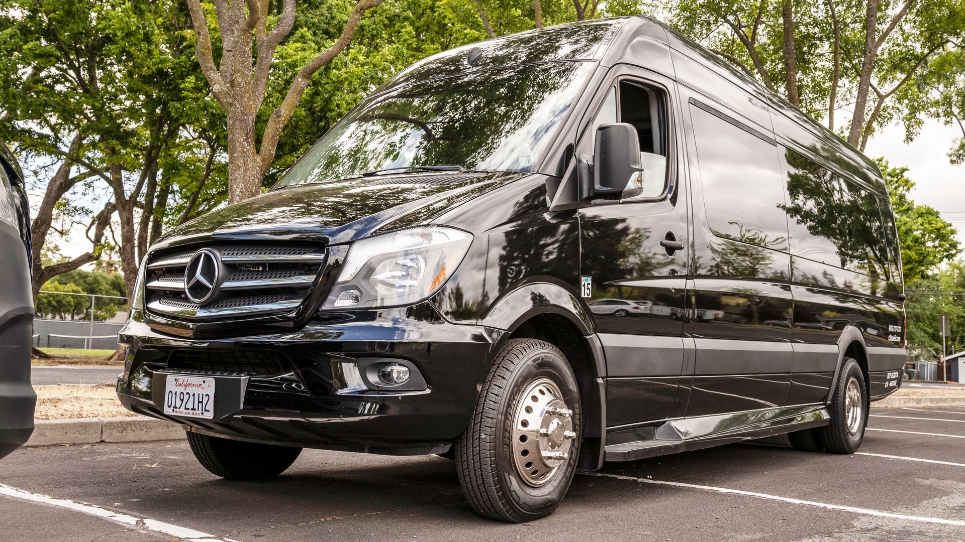 A black van is parked on the side of the road in front of a building.