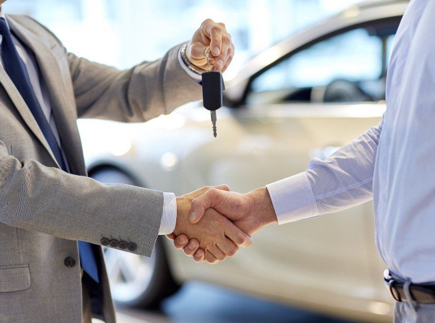 a man is shaking hands with another man while holding a car key
