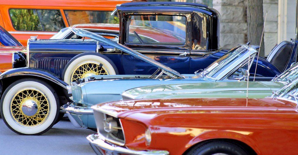 a row of old cars are parked next to each other on a street .