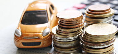 a toy car is sitting next to a pile of coins and a calculator .