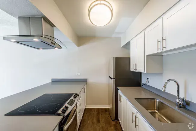 Modern kitchen with white cabinets, grey countertops, and stainless steel appliances.