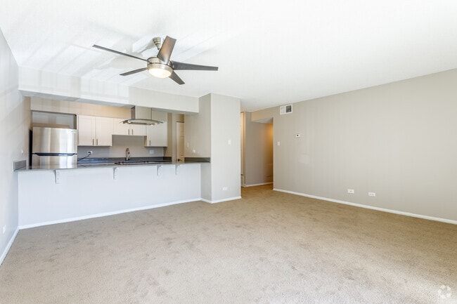 Spacious living room area featuring carpet and ceiling fan.