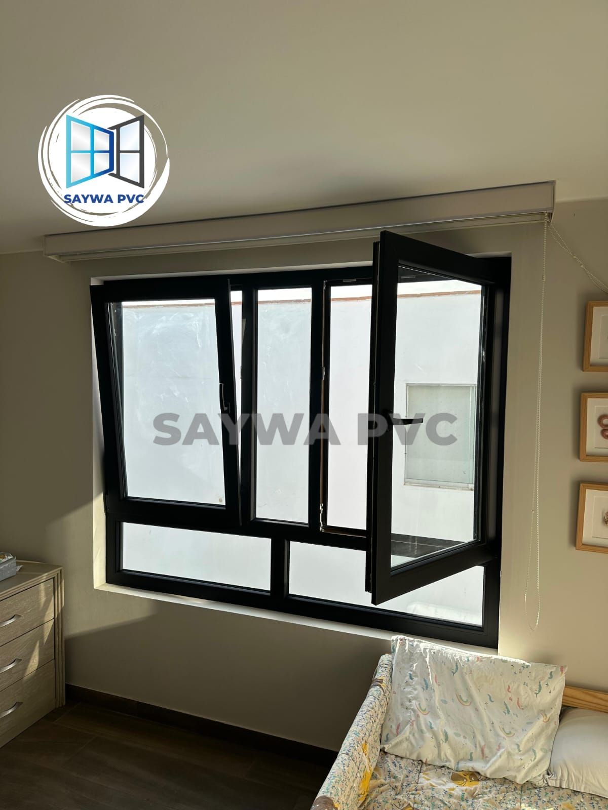 Una moderna ventana abatible de PVC con marco negro instalada en una habitación, con un panel abierto.