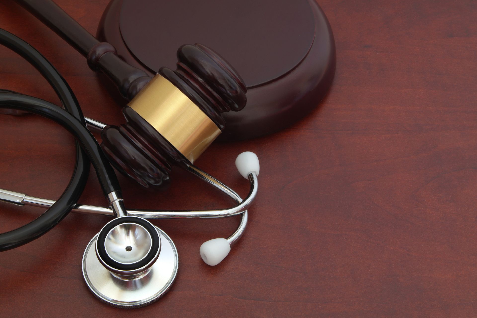 Gavel and stethoscope on a wood surface, symbolizing healthcare law.