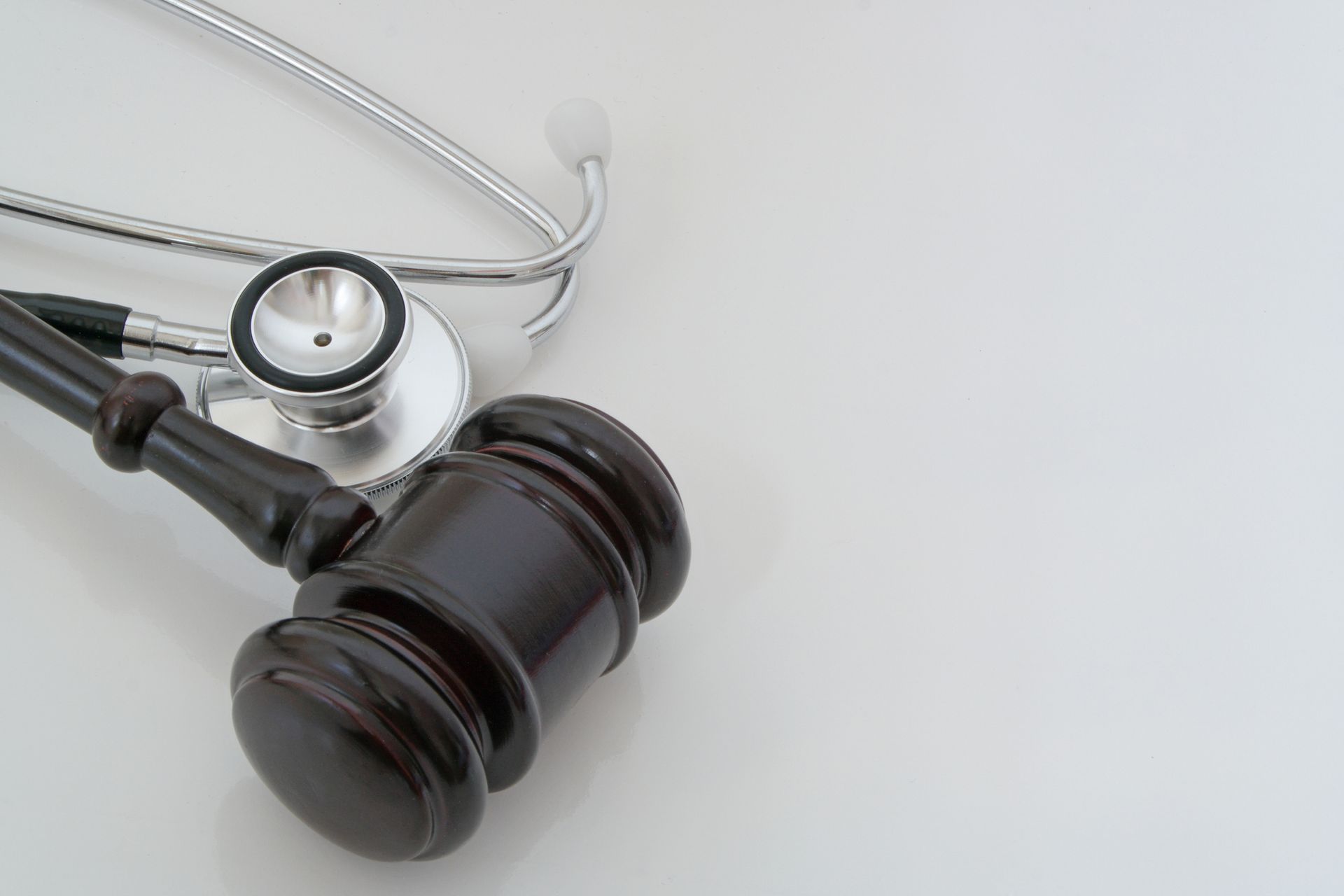 Gavel and stethoscope on a white surface, suggesting medical malpractice or legal considerations in healthcare.