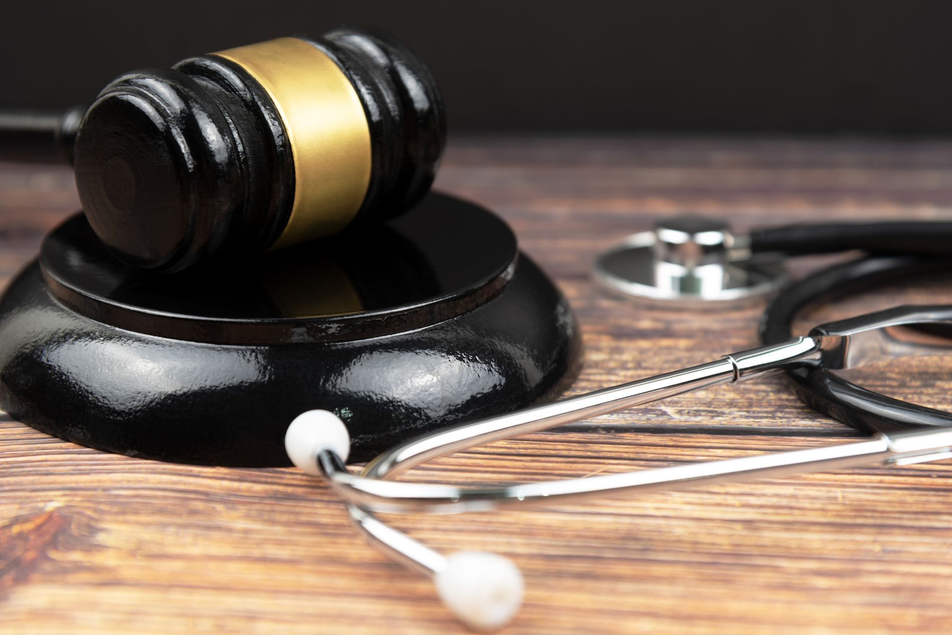 A judge 's gavel and stethoscope are on a wooden table. A judge 's gavel and stethoscope are on a wooden table.