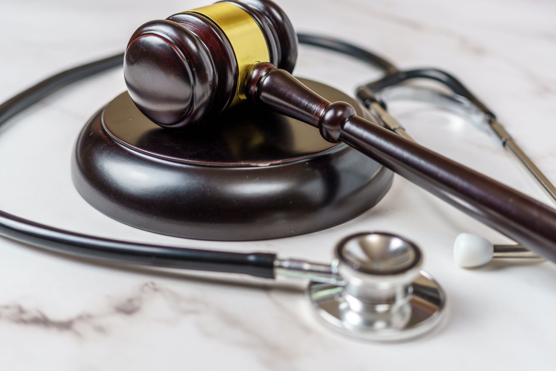 Gavel and stethoscope on marble surface, symbolizing medical law and legal proceedings. Gavel and stethoscope on marble surface, symbolizing medical law and legal proceedings.