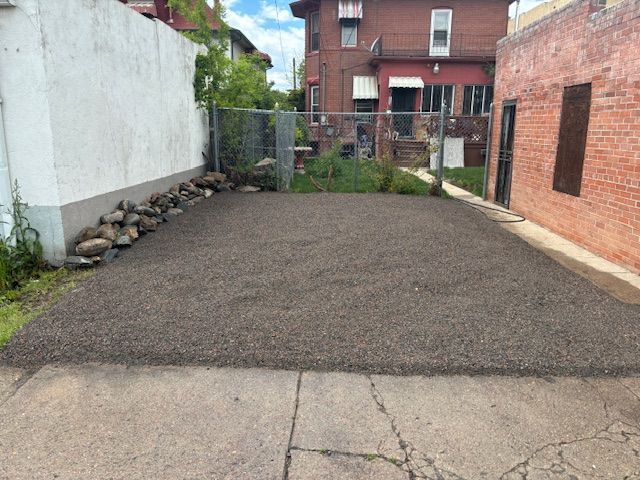 A brick building with a gravel driveway in front of it.