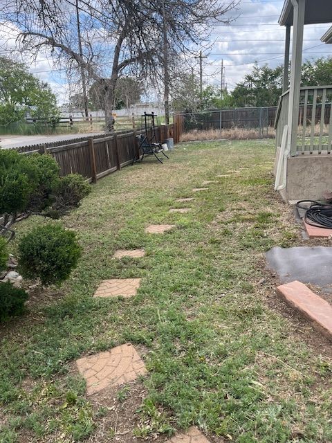 A lawn with a fence and a porch in the background