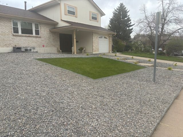 A house with a gravel driveway and a large lawn in front of it.
