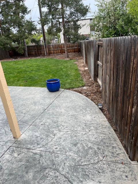A blue pot is sitting on a patio next to a wooden fence.