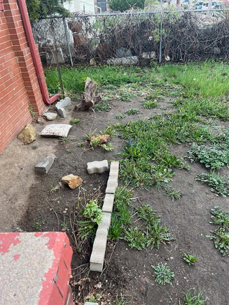 A backyard with a lot of grass and bricks in it.