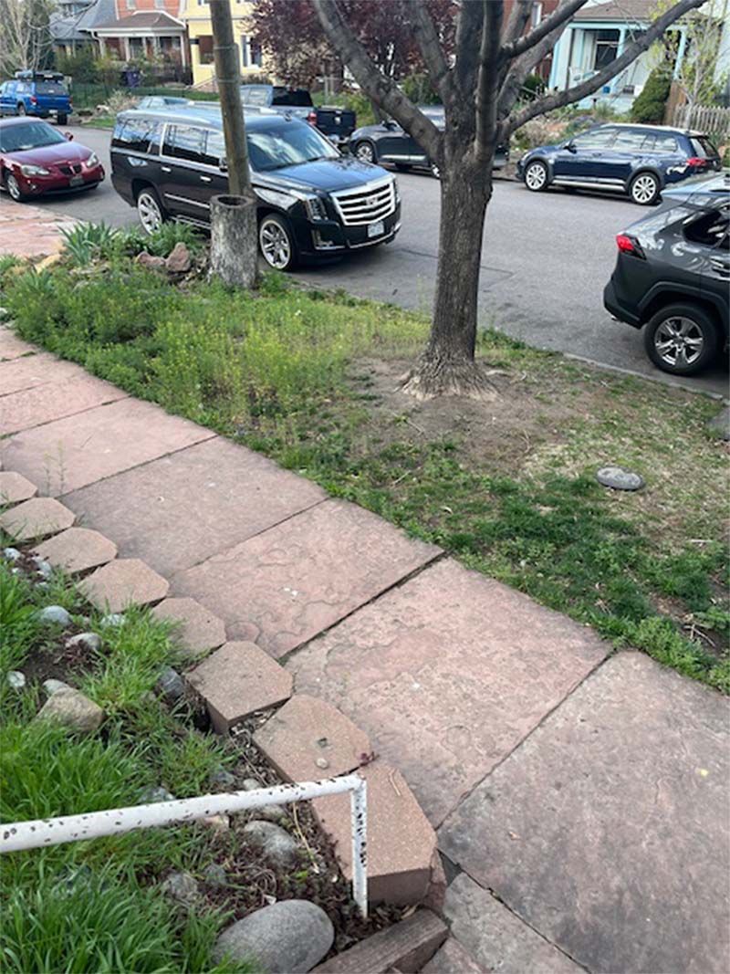 A sidewalk with cars parked on the side of it.