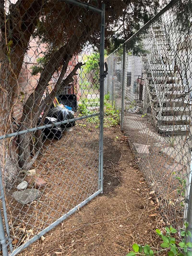 A chain link fence surrounds a dirt path leading to a staircase.