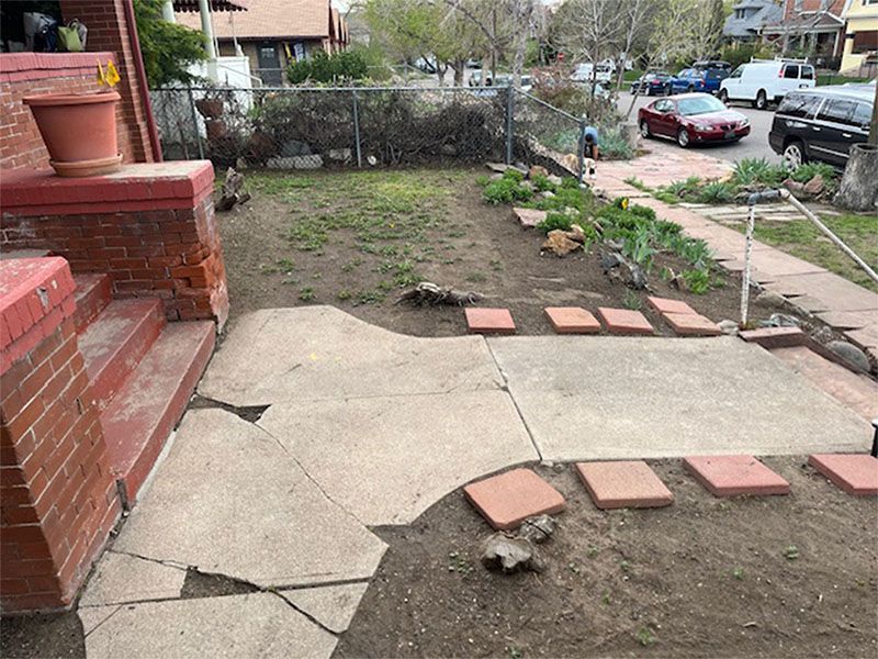 A concrete walkway is being built in the backyard of a house.
