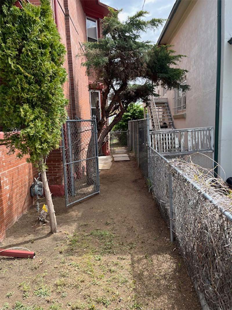 There is a chain link fence between two houses.