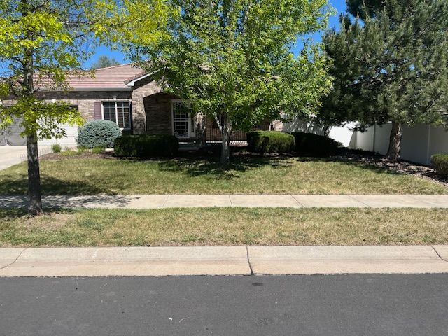 A house with a lush green lawn and trees in front of it.