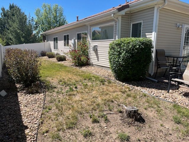The backyard of a house with a white fence and a lot of grass.