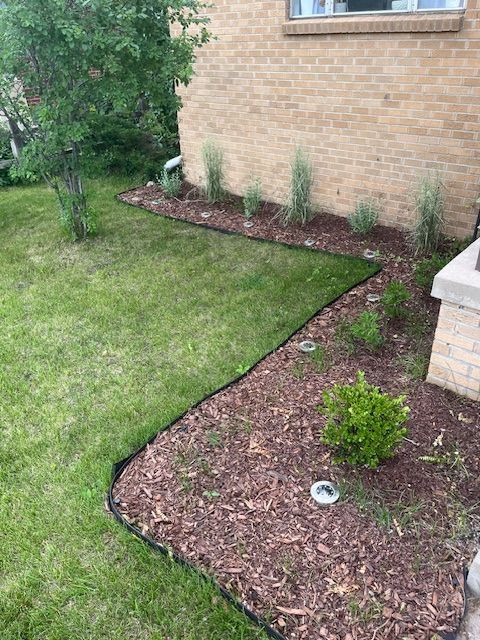 A brick house with a lush green lawn and a garden in front of it.