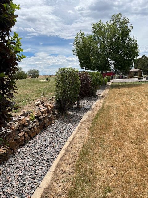 A gravel path leading to a grassy field with trees in the background
