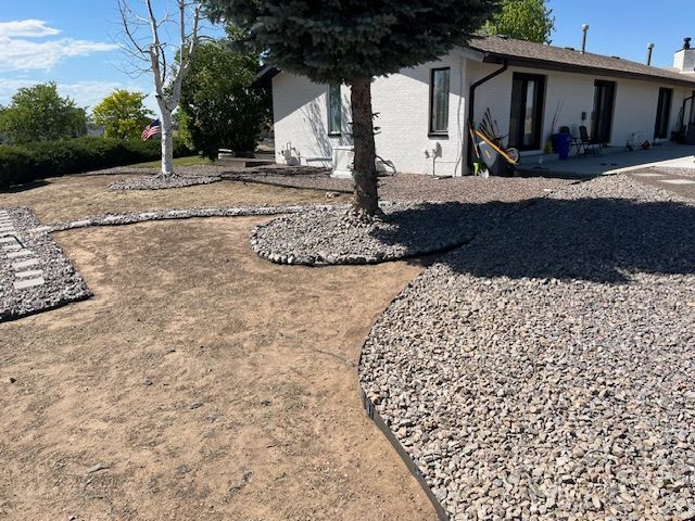 A house with a gravel driveway and a tree in front of it.
