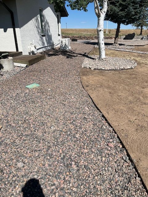 A gravel path leading to a house with a tree in the background.