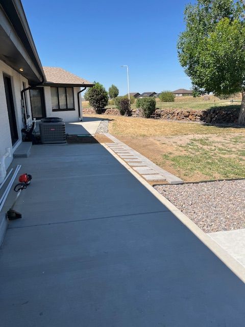 A concrete walkway leading to a house on a sunny day.