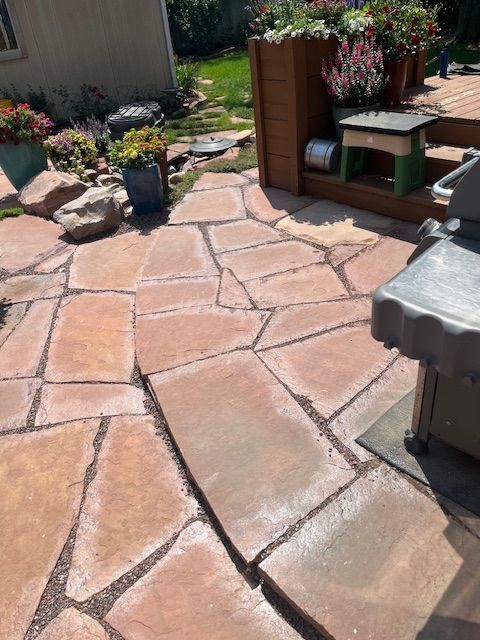 A patio with a grill and flowers on it