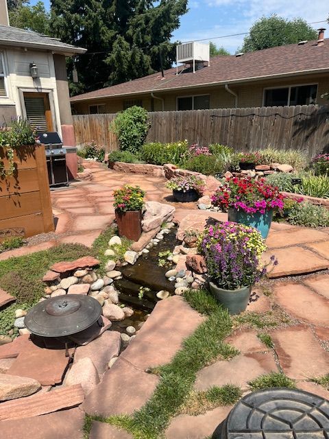 A patio with flowers and rocks in front of a house.
