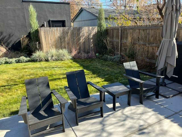 Three chairs and a table are sitting on a patio in a backyard.