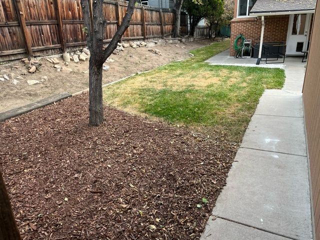 A backyard with a concrete walkway and a wooden fence.