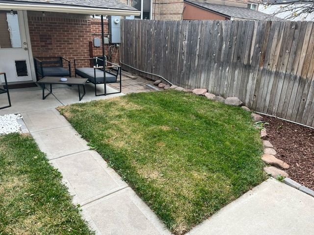 A backyard with a wooden fence and a patio area.