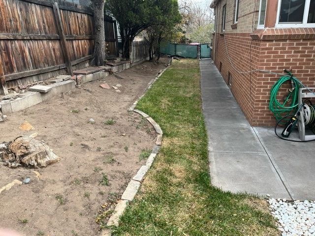 A sidewalk leading to a house with a hose on the side of it.