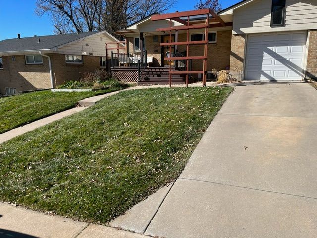 A driveway leading to a house with a lush green lawn