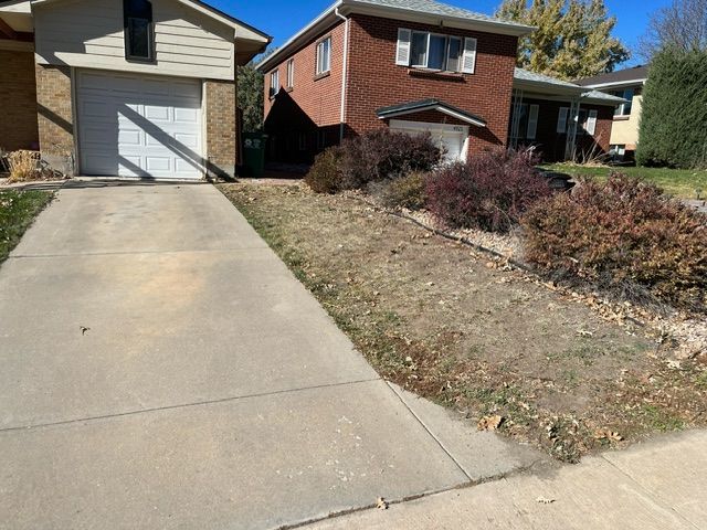 A driveway leading to a brick house with a white garage door.