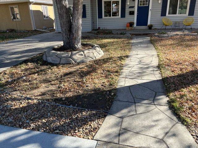 A stone walkway leading to a house with a tree in the middle of it.