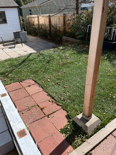A backyard with a brick walkway and a wooden fence.