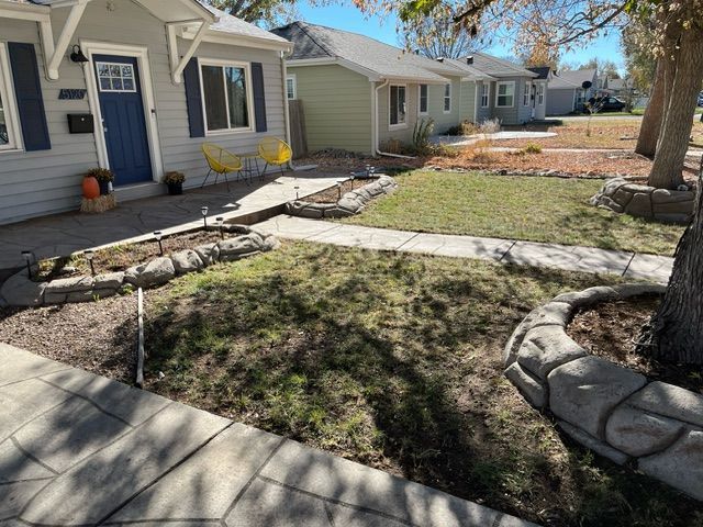 A house with a blue door and a sidewalk in front of it.