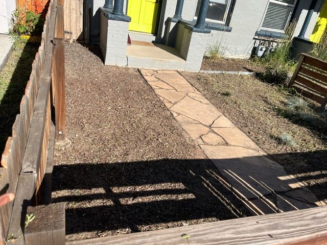 A stone walkway leading to a house with a yellow door
