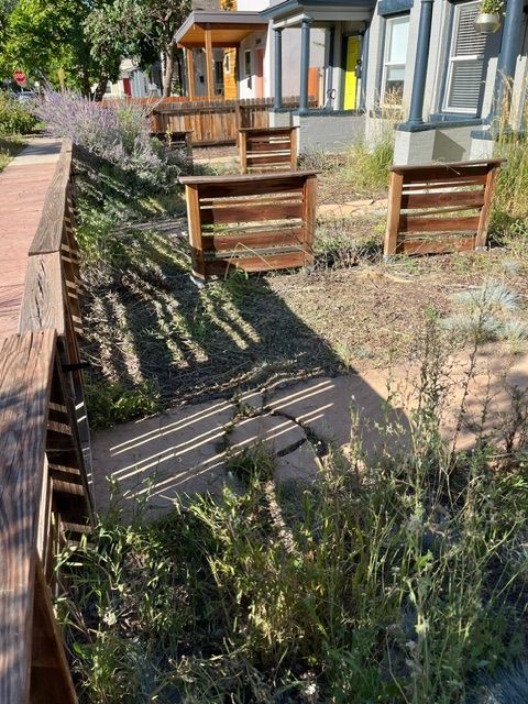 A row of wooden benches are sitting in front of a house.