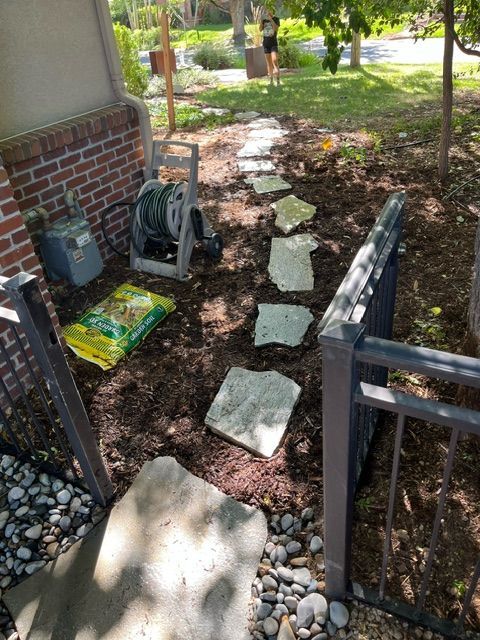 A stone walkway is being built in the backyard of a house.