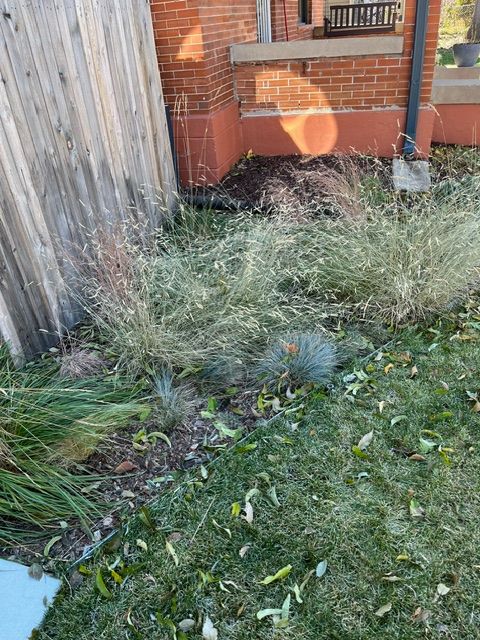 A brick building with a wooden fence and a lot of grass in front of it.