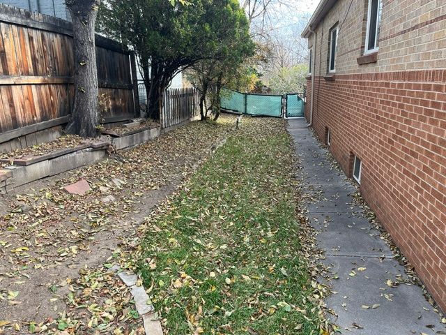 A sidewalk leading to a brick house with a wooden fence.