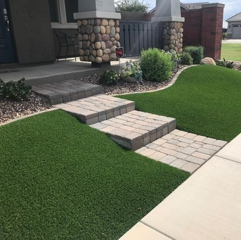 Steps leading to a house entrance surrounded by green turf and landscaping.