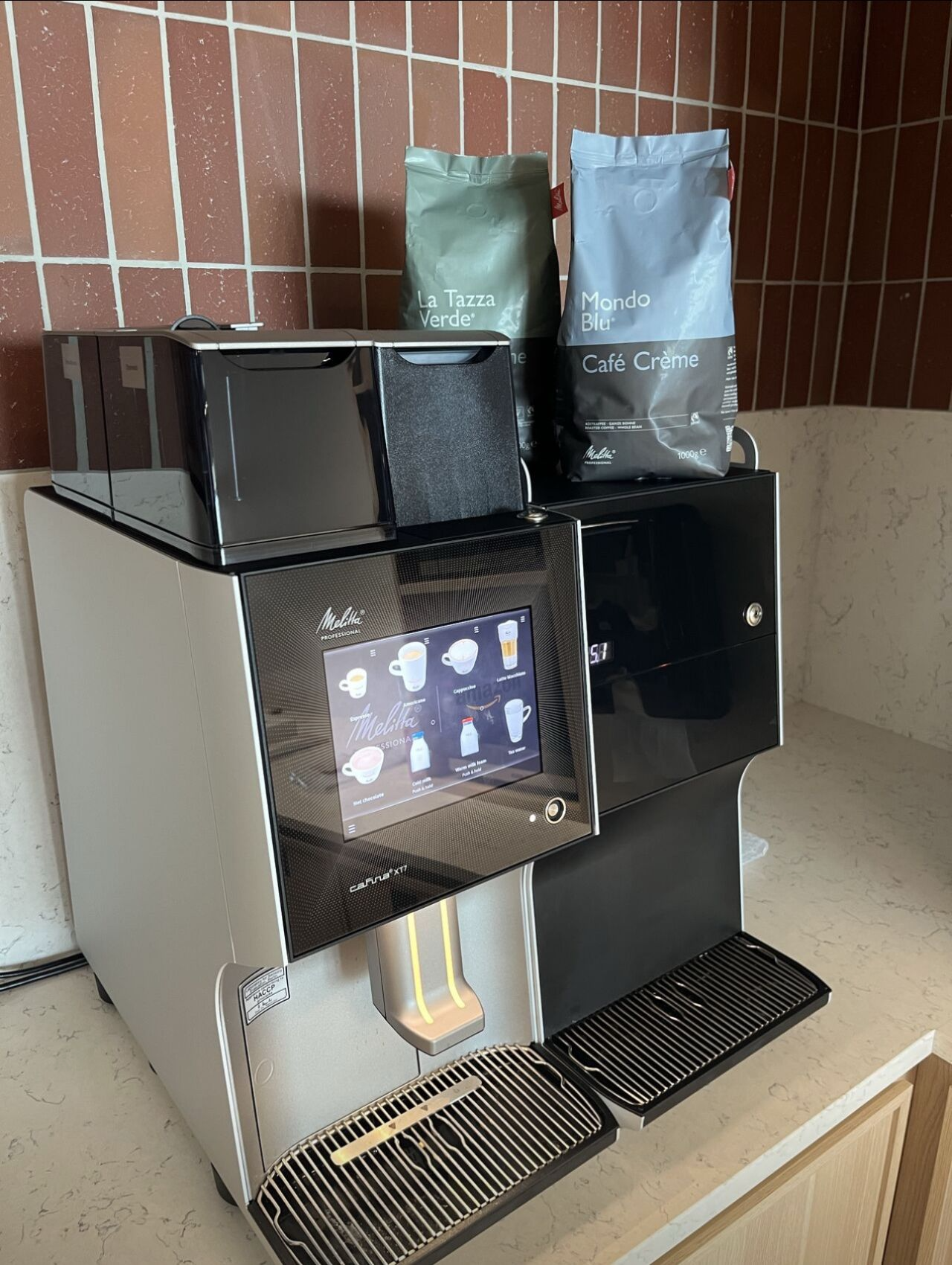 A coffee machine is sitting on a counter next to two bags of coffee.