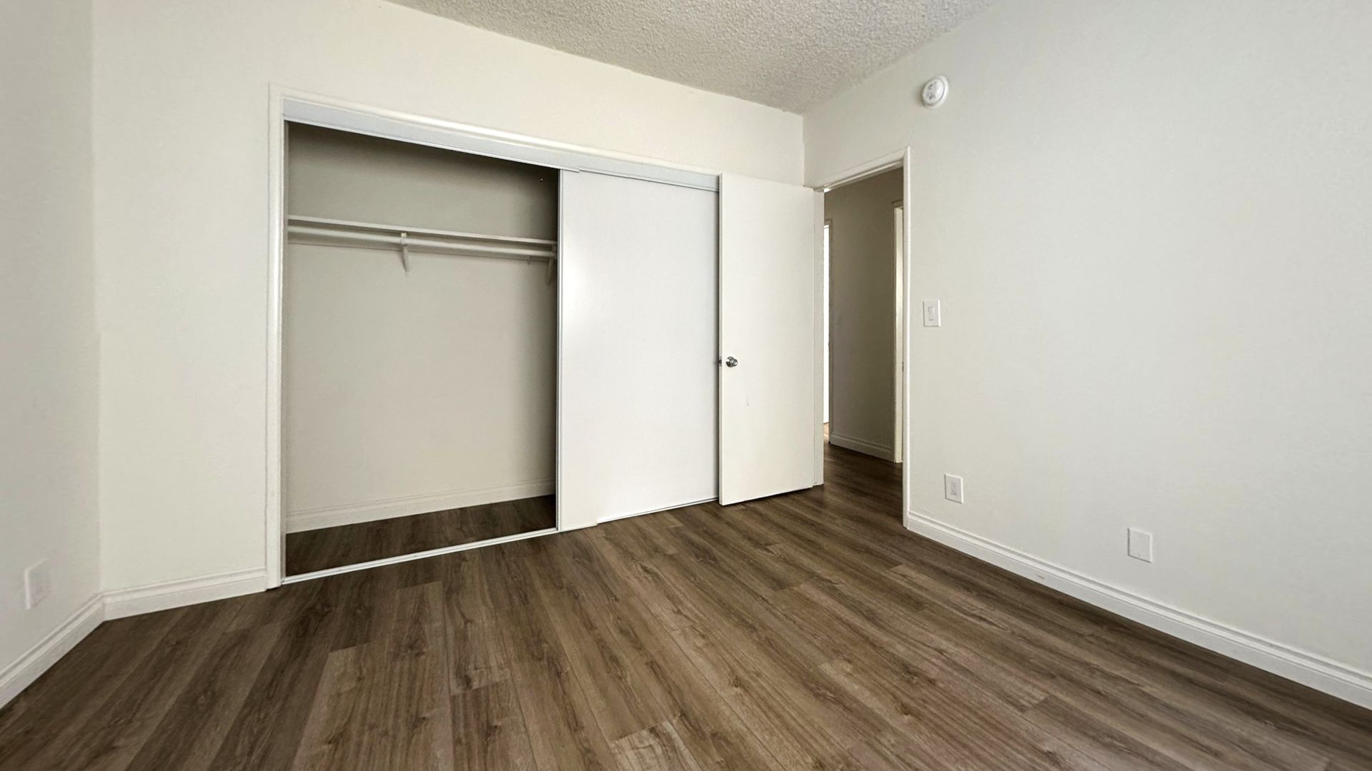 Empty room with closet and hardwood floors. White walls and ceiling, closet has sliding doors.