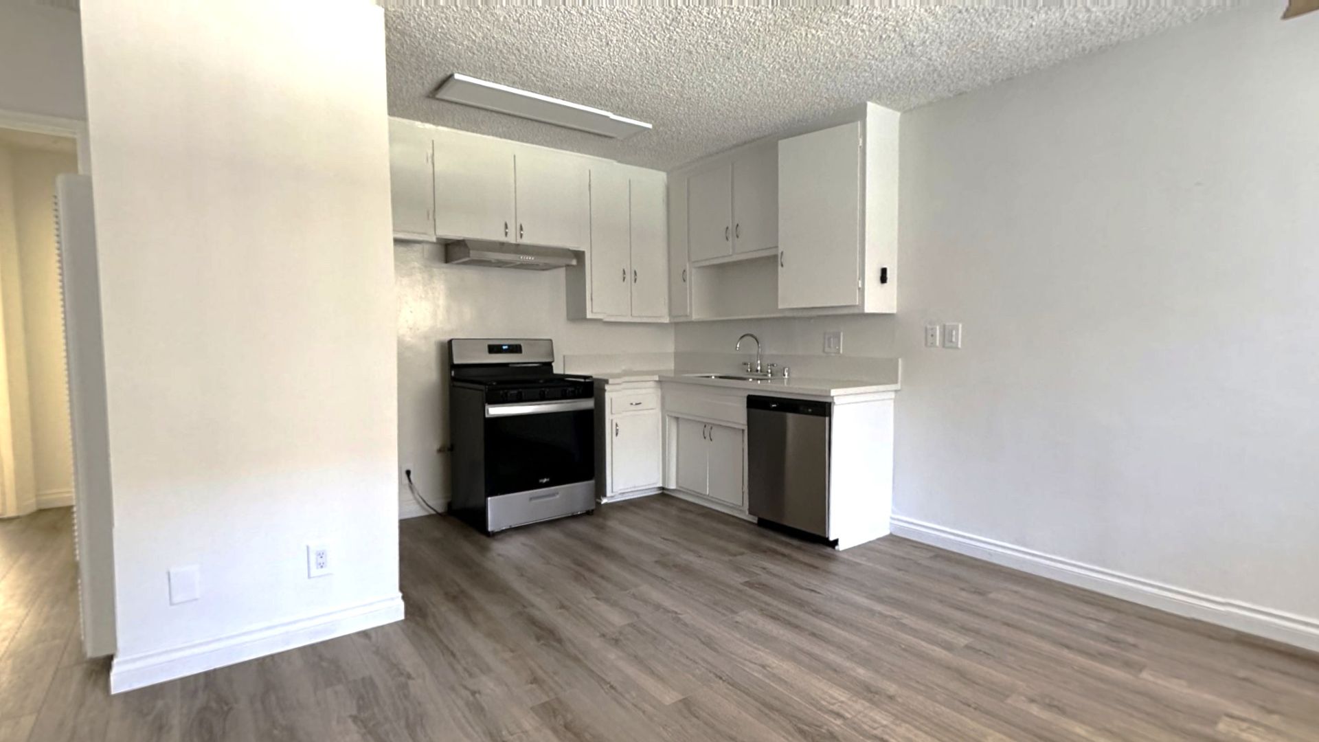 Kitchen with white cabinets, stainless steel appliances, and gray flooring.