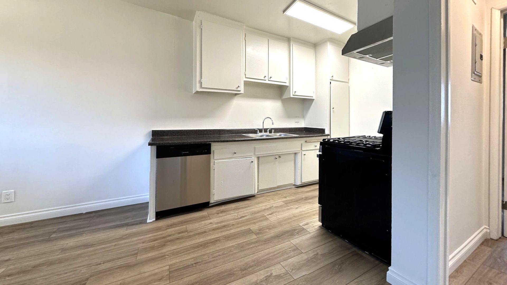 Kitchen with white cabinets, stainless steel appliances, and wood-look flooring.