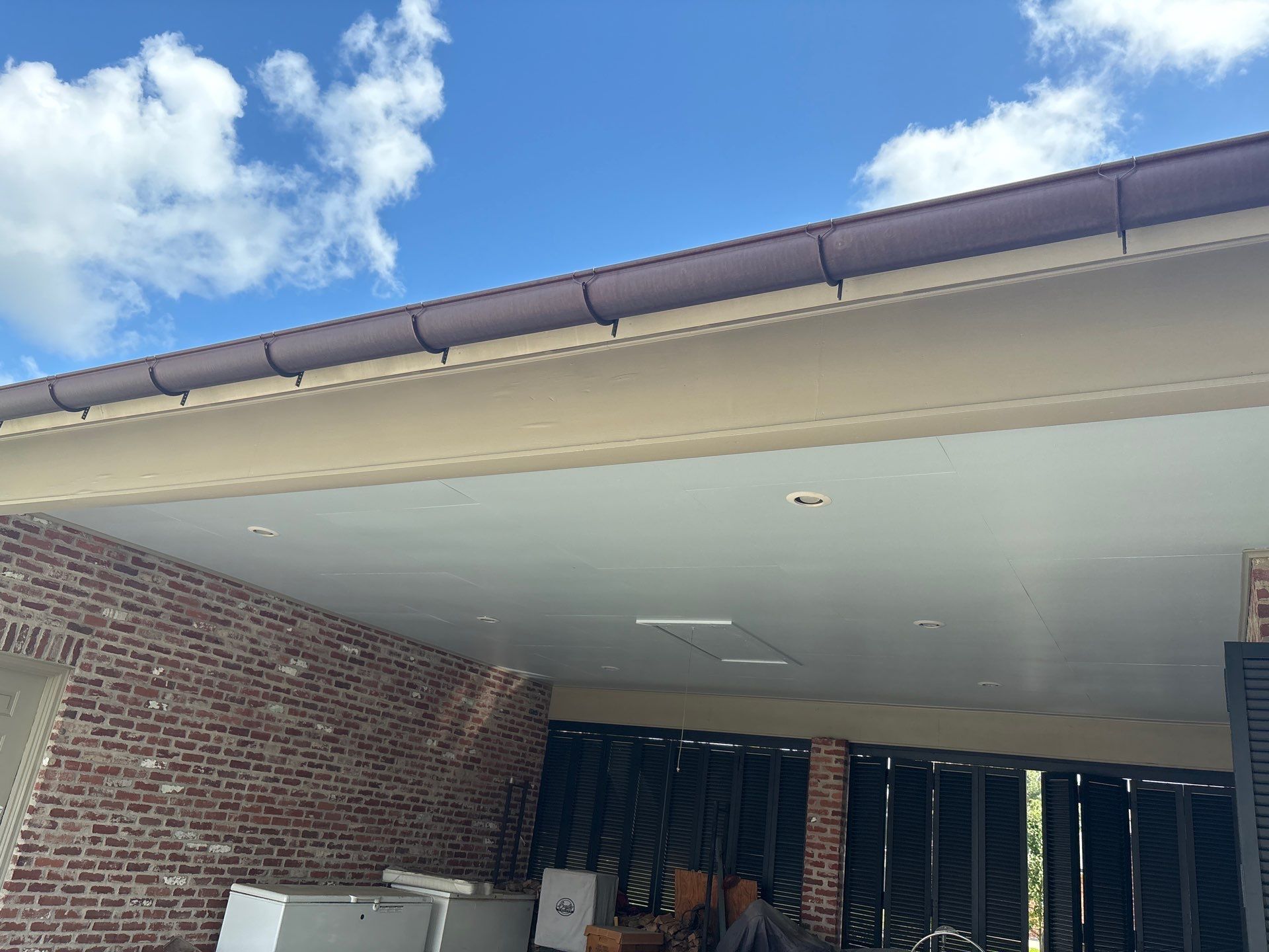Brick building exterior with brown trim under a blue sky.