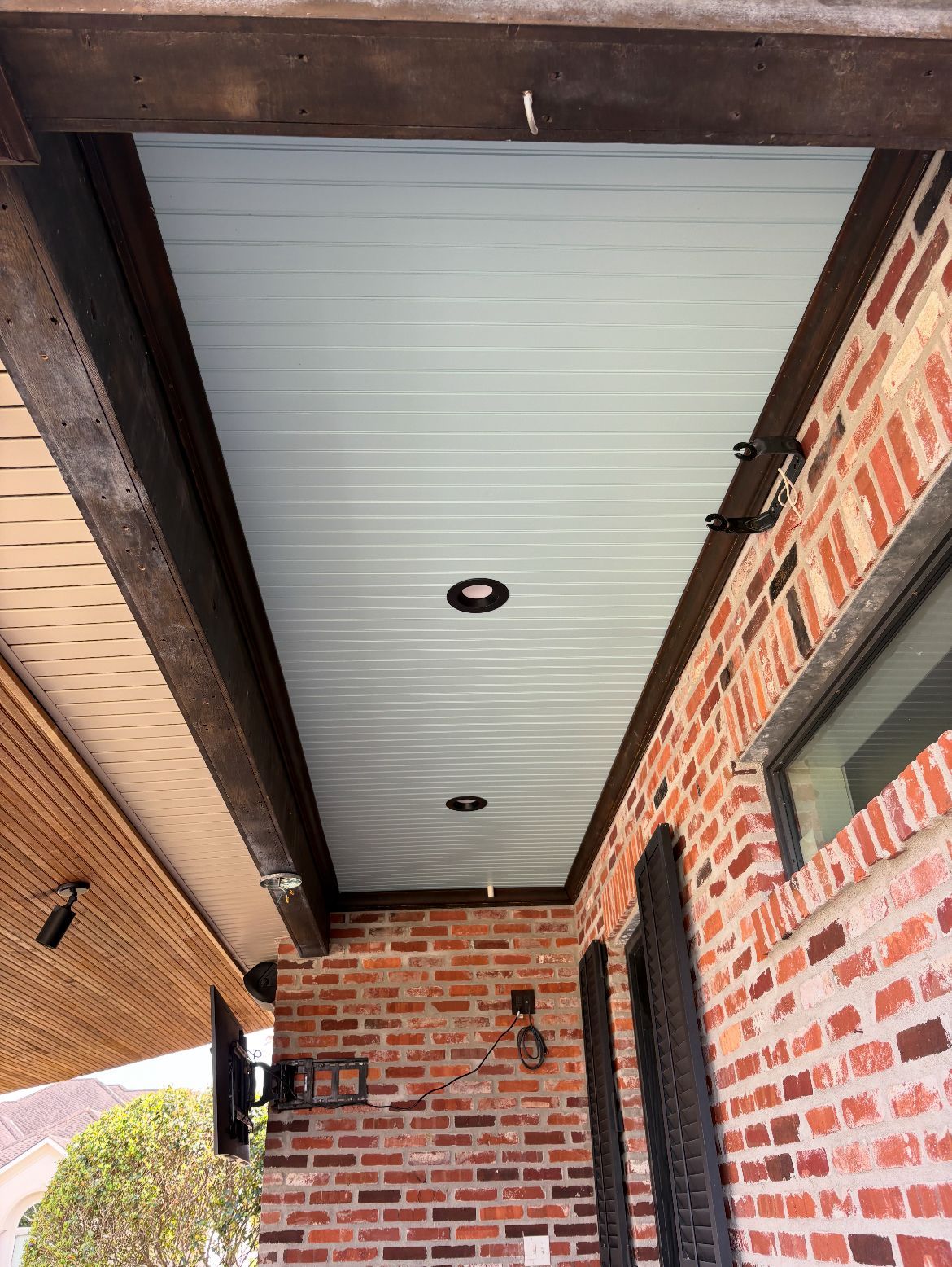 The ceiling of a porch with a brick wall and a white ceiling.